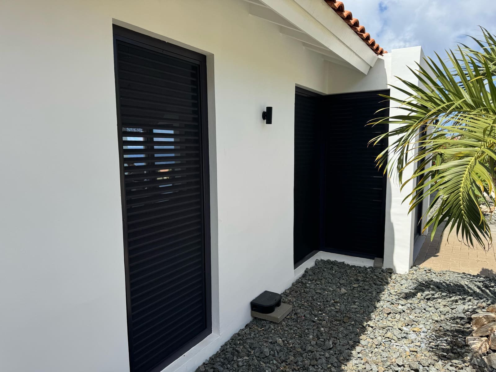 Fixed insect screens on black louvered openings in Curaçao