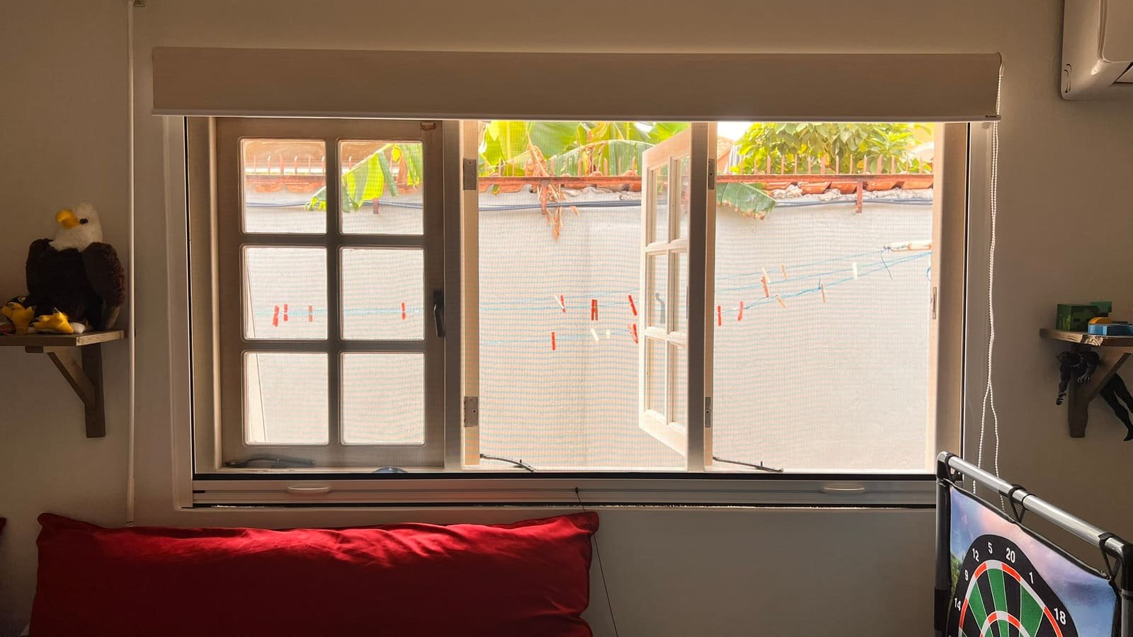 Roll-up window screen, with the sash open behind the mesh in Curaçao
